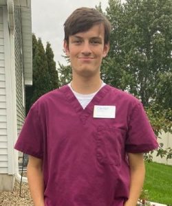 Youth apprentice poses for photo wearing purple scrubs.