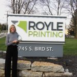 Dawn recieves the Champions in Action Award by the Royle Printing sign